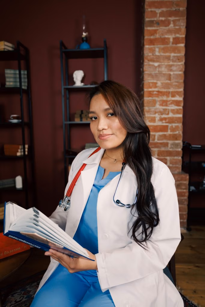 Young female doctor reads a medical book in a study, conveying professionalism and expertise.